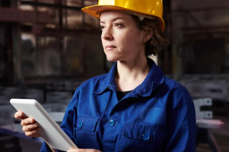 Female construction worker wearing blue uniform and yellow hard hat
