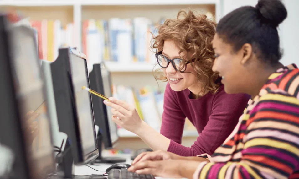 Teachers aid helping a student with an assignment on a computer